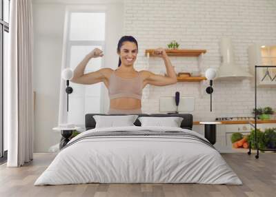 Energetic body conscious blogger in activewear filming vlog on vegetarian diet and healthy eating habits. Happy young woman recording video, showing fit strong body and sharing fitness success advice Wall mural