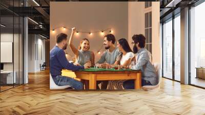 Excited young woman celebrating poker victory sitting at table with friends at casino themed party Wall mural