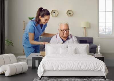 Friendly smiling nurse caregiver in geriatric clinic or retirement home helps senior man with Alzheimer's disease. Happy old man plays puzzles while sitting at table in cozy interior. Dementia concept Wall mural