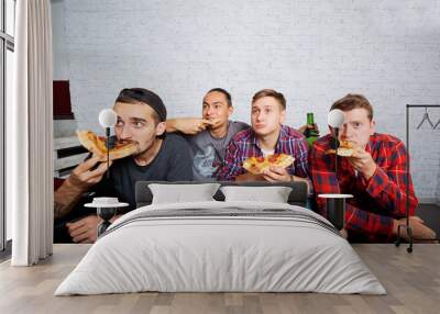 Friends watching TV with surprise, eating pizza close-up. Fans w Wall mural