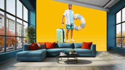 Full body photo of a funny young happy man tourist in rubber ring hurrying up on summer holiday trip in office clothes isolated on studio yellow background. Vacation and travel concept. Wall mural