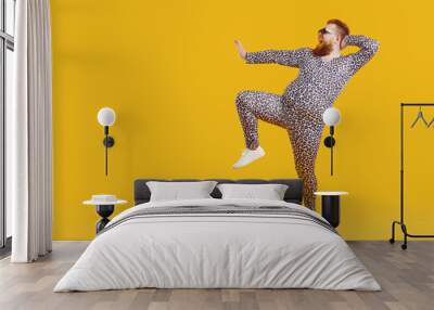 Funny fat fashion guy in pajamas posing on copy space background. Full length portrait of happy joyful plump bearded young man wearing crazy leopard PJs dancing on blank yellow copyspace background Wall mural