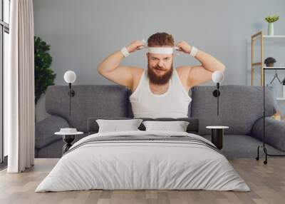 Funny fat man in sportswear is sitting on the sofa in the room Wall mural