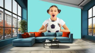 Funny girl child isolated on blue studio background hold ball cheer support sport team. Happy excited teen kid scream and yell for favorite football team goal score. Children hobby concept. Wall mural