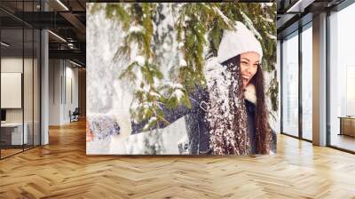 Girl under falling snow from a tree in the park in winter. Wall mural