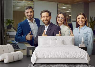 Group of business people men and women looking at camera, showing thumbs up sign and smiling. Company employees team or a group of staff standing in office confidently and cheerfully on workplace. Wall mural