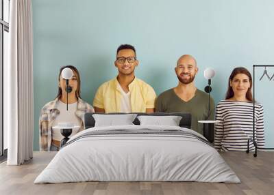 Group of cheerful, smiling mixed race multi ethnic youth. Diverse team of young people with happy faces standing in row and looking at camera against blue studio background. Website banner or header Wall mural