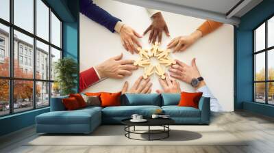 Group of diverse people arrange human figures in circle. Team of multiethnic business partners join little wooden figures on table. Teamwork, community, working together and cooperation metaphor Wall mural