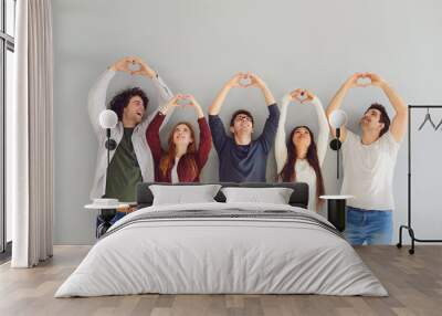 Group of friends making heart sign with hands on gray background. Wall mural