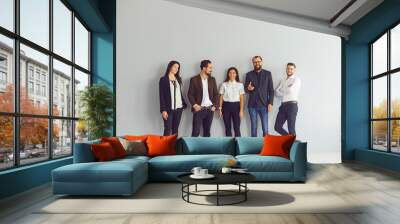 Group of happy young business people standing near studio wall looking at camera Wall mural