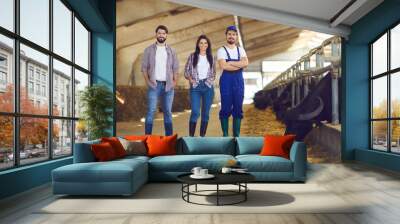 Group of happy young cattle farm workers standing in a livestock barn and smiling Wall mural