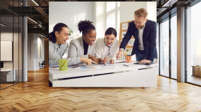 Group of young people meeting around office table. Happy successful business team sitting at desk, working on project, analyzing data report, setting goals, developing new product, enjoying teamwork Wall mural