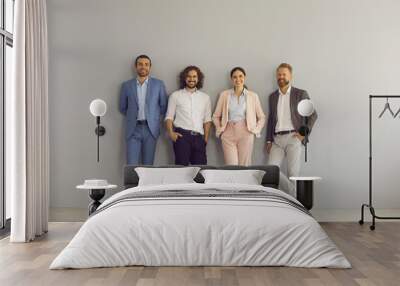 Group portrait of four successful young business people in formal and smart casual wear. Team of 4 happy colleagues or professional executive managers standing together near grey studio or office wall Wall mural