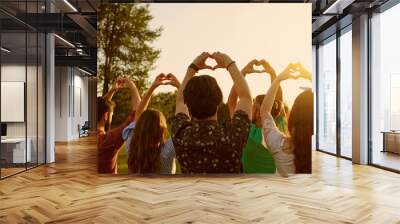 Hand sign heart. A group of people holds hands with a heart sign on a sky background with sunset on nature. Wall mural