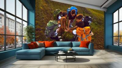 Handshake of young smiling tourists hikers standing in circle and hiking together on nature Wall mural