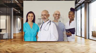 Happy diverse multiracial staff of clinic or hospital. Team of mixed race doctors, including clinicians and cardiologists, in scrubs and white lab coat uniforms standing together and smiling at camera Wall mural