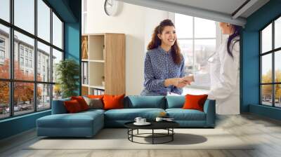 happy doctor and patient shaking hands. friendly physician greeting her new female patient. beautifu Wall mural