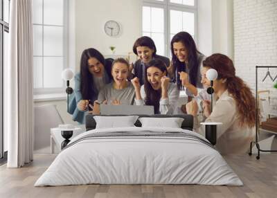 Happy excited business women looking at laptop computer, cheering and shouting for joy. Team of jubilant lucky young workers celebrating successful project realization, making deal or signing contract Wall mural