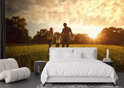 Happy family walks on the park at sunset. Wall mural