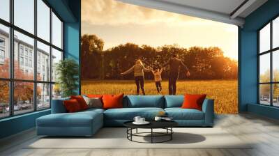 Happy family walks on the park at sunset. Wall mural