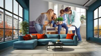 Happy family with two children moving into new house. Young parents with son and daughter having fun in their new home new house with cardboard boxes. Smiling little children sitting on table Wall mural