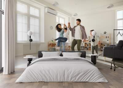 Happy joyful family having fun at home. Cheerful excited sister and brother with mom and dad playing and enjoying leisure time together in modern white living room of their new cozy house or apartment Wall mural