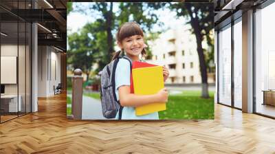 Happy little student girl with a backpack on her way to school. Wall mural