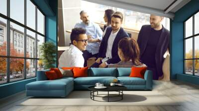 Happy people standing in modern office and talking. Multiracial group of men and women discussing team training workshop they have just attended. Employees having break during business seminar Wall mural