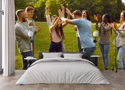 Happy students friends standing together outdoor in summer park having fun in nature and enjoying meeting on holidays. Group of a young people walking in garden and having weekend activity. Wall mural