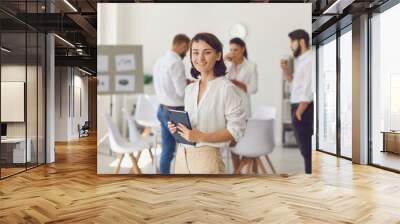 Happy successful businesswoman or company leader standing in office looking at camera and smiling Wall mural