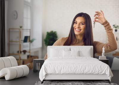 Happy woman holding keys to new home, looking at camera and smiling. Portrait of first time buyer, house owner, apartment renter, flat tenant or landlady. Moving day and buying own property concept Wall mural