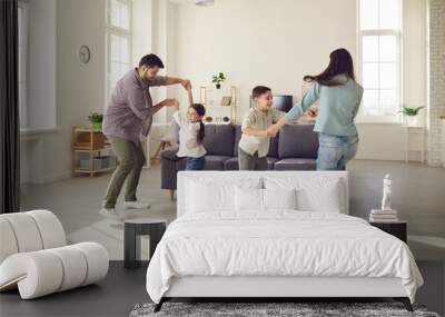 Happy young family with kids enjoying free time on weekend at home. Parents and children dancing and having fun in spacious living-room, celebrating moving into new house or rented apartment Wall mural