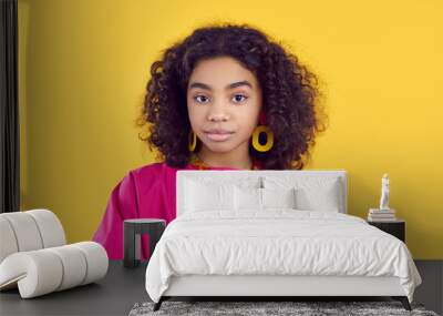 Head shot of kid in fashion studio. Portrait of beautiful child model. African American girl wearing fuchsia top, hoop earrings and plastic necklace looking at camera with confident face expression Wall mural