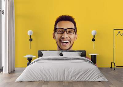 Headshot of student with happy face expression isolated on solid yellow background. Studio portrait of cheerful excited young black man in glasses looking at camera, smiling and laughing sincerely Wall mural