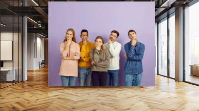 Hmm. Group of curious multiracial people with hands on chins and puzzled face expressions, look up, think hard, answer difficult question, doubt, reflect on serious problem, choose future career plans Wall mural