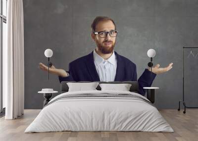 Irritated adult caucasian businessman with displeased face expression in formal suit showing so what or dont know gesture studio headshot. Confused man shrugging up looking at camera portrait Wall mural