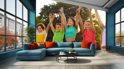 Little kids playing and having fun in green park. Group of happy, joyful children standing in row, smiling and raising hands up. Banner, header. Sun flare. Summer, vacation, fun, friendship concept Wall mural