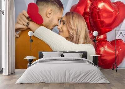 Loving, happy, beautiful, young couple at home in romantic atmosphere congratulate each other on Valentine's Day, hug each other looking into each other's eyes. Wall mural