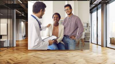 Male doctor comfort support multiracial couple patients at consultation in clinic. Man gynecologist caress show help understanding to ethnic family at hospital appointment. Good medicine concept. Wall mural