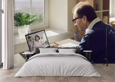 Male patient consulting online doctor at home. Mature man using laptop computer and communicating with nurse or general practitioner. Telemedicine, virtual visit to clinic, video conference concept Wall mural