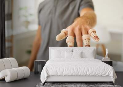 Man who has hurt his fingers is wearing adjustable finger splint braces. Close up shot of a guy showing his hand with beige support braces on his injured fingers and thumb. Injury treatment concept Wall mural