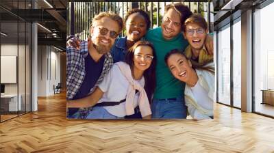 Multiracial young people university students dressed in casual clothes with smile pose for friendly portrait after completing their studies or entering city college stand on sidewalk in summer day Wall mural