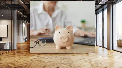 Piggy bank in form of pig on background of financial advisor who plans annual budget. Close up of piggy bank on table. Business, finance, investment, saving and corruption concept. Wall mural