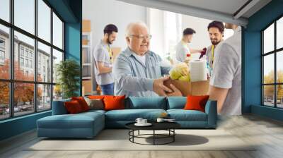 Poor old man gets food aid. Senior citizen who belongs to vulnerable social group gets help at charity organization. Thankful grateful aged man takes grocery box at community centre. Donation concept Wall mural