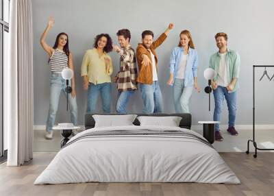 Portrait of a group of young happy smiling friends students or colleagues in casual clothes standing together, looking positively at the camera and having fun on a grey background. Wall mural