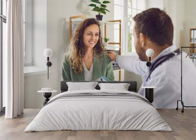 Portrait of a male doctor support young smiling female patient putting hand on her shoulder. Physician sitting in medical clinic giving consultation a woman during medical examination in office. Wall mural