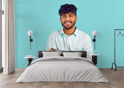 Portrait of happy ethnic student. Cheerful young dark skinned Indian, Arab, Gypsy or Bangladeshi man with curly black hair in white shirt standing with his arms folded, looking at camera and smiling Wall mural