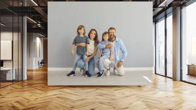 Portrait of happy smiling European family in comfortable clothes. Cheerful mother, father and children posing in studio. Positive young mum, dad and kids in modern jeans and T shirts looking at camera Wall mural