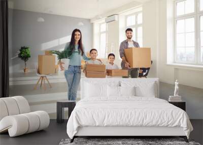 Portrait of happy smiling family in new home holding unpacked cardboard boxes. Little boy and girl helping mom and dad on moving day. Concept of real estate, buying house or apartment and relocation Wall mural