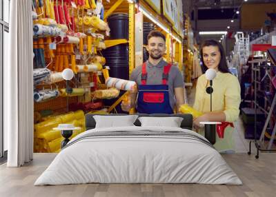 Portrait of smiling salesman and happy female client in household or diy hypermarket. Male consultant or assistant consult woman customer with paint and brush choice in household store. Wall mural